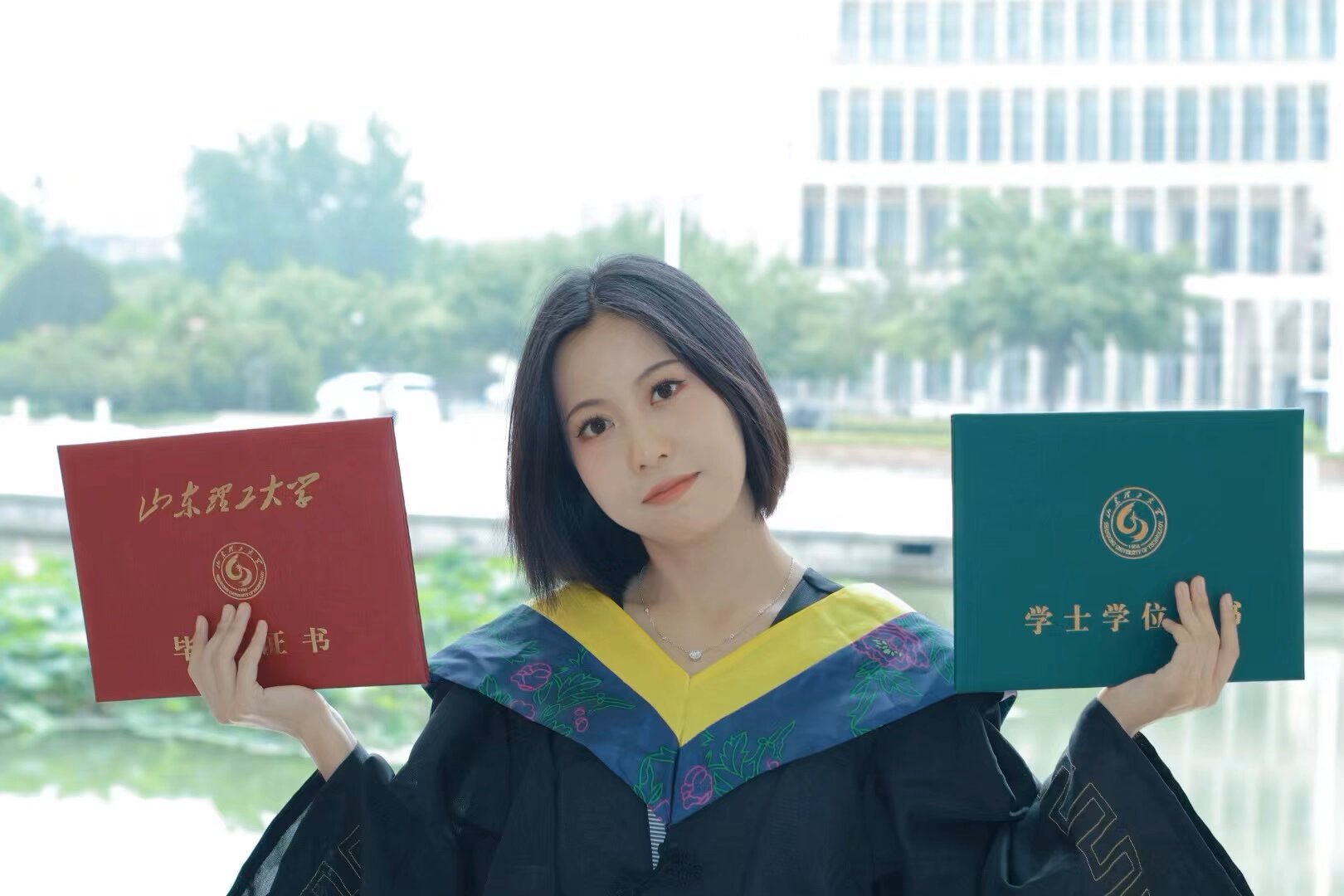 Wenxiu Wei in graduation attire holding her diploma and bachelor's degree certificates